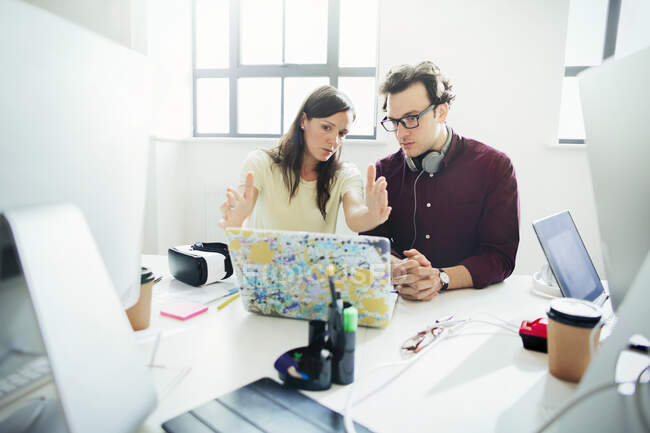 Designers brainstorming, gesturing at laptop in office — Stock Photo