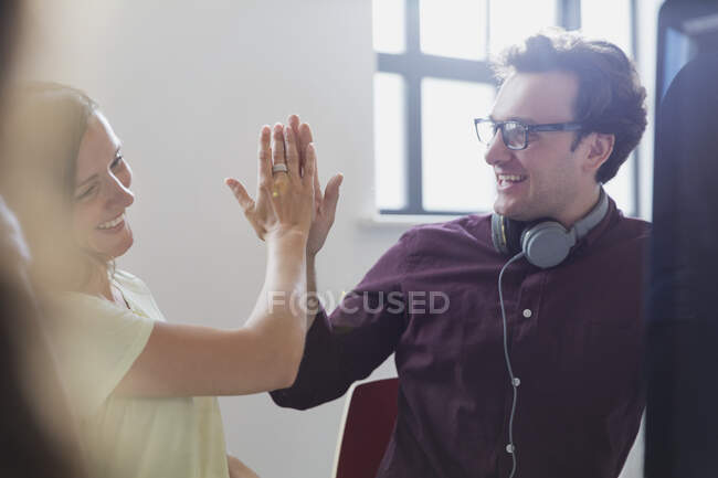 Enthusiastic creative business people high-fiving in office — Stock Photo