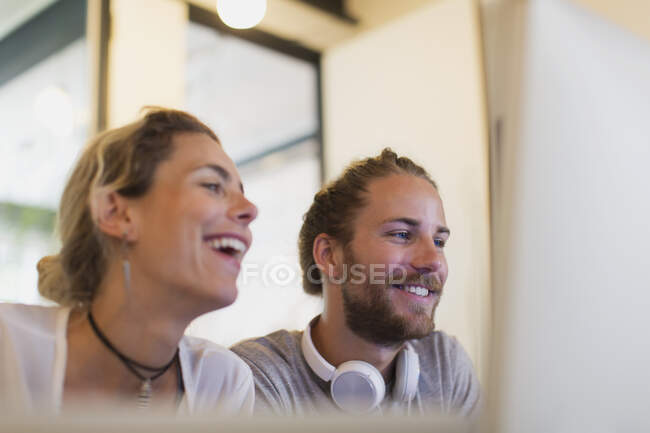 Счастливые дизайнеры, работающие за компьютером в офисе — стоковое фото