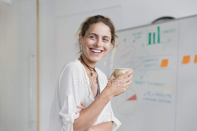 Уверенная, улыбающаяся деловая женщина пьет кофе в конференц-зале — стоковое фото