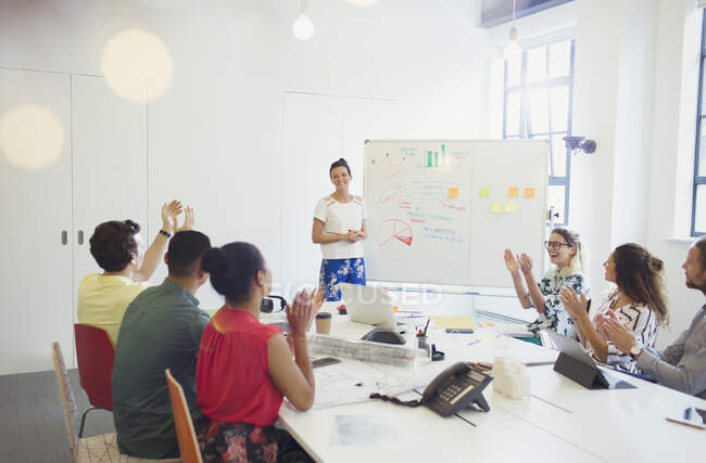 Supportive colleagues clapping for female architect leading meeting at whiteboard — Stock Photo