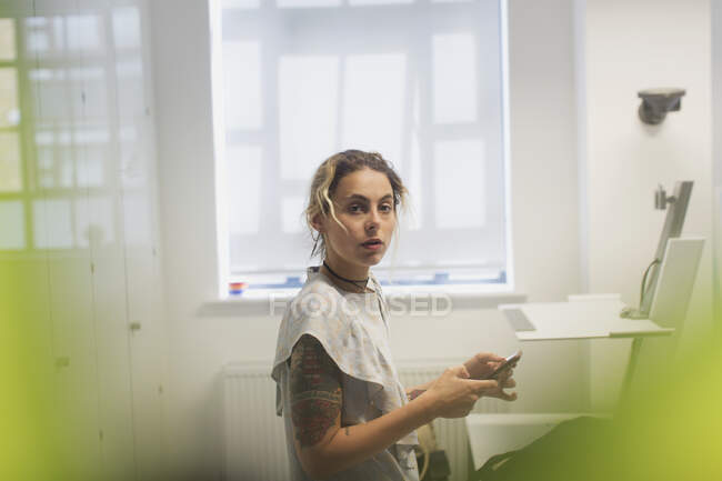 Retrato sério designer feminino em pé na mesa — Fotografia de Stock