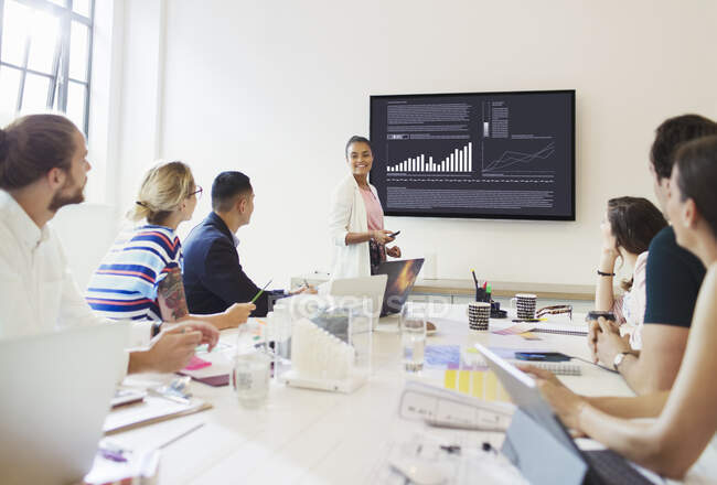 Confident businesswoman at television screen leading conference room meeting — Stock Photo