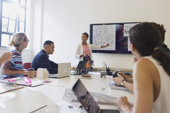 Female architect at television screen leading conference room meeting — Stock Photo