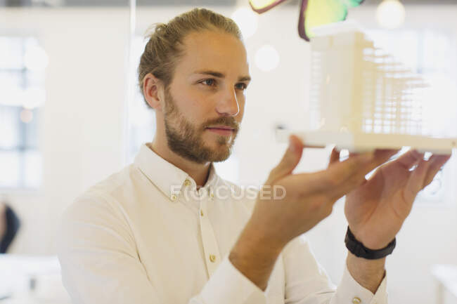 Arquitecto masculino enfocado y curioso examinando modelo en la oficina - foto de stock