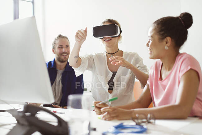 Programadores informáticos probando gafas de simulador de realidad virtual en la computadora en la oficina - foto de stock