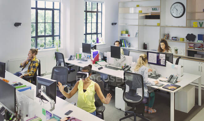 Diseñadores trabajando en escritorios en oficinas de planta abierta - foto de stock