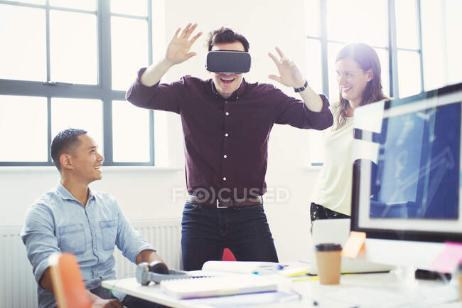 Programadores informáticos probando gafas de simulador de realidad virtual en la oficina - foto de stock