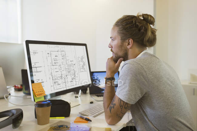 Ориентированный мужчина-архитектор просматривает цифровой чертеж на компьютере — стоковое фото