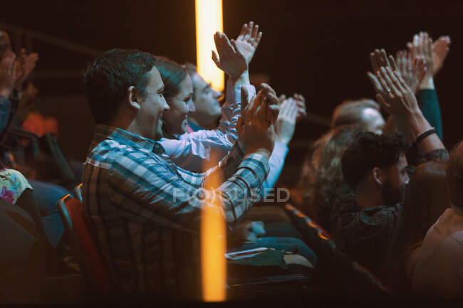 Audience clapping in dark room — Stock Photo