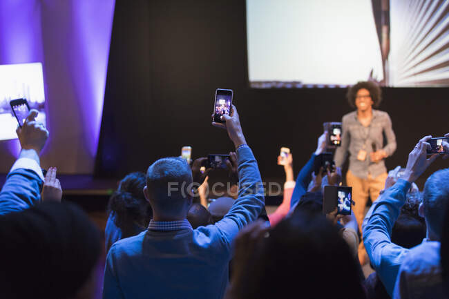 Membres du public avec téléphones intelligents vidéoconférence haut-parleur sur scène à la conférence — Photo de stock