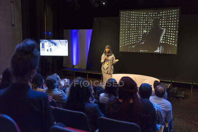 Женщина-спикер в хиджабе на сцене разговаривает с аудиторией конференции — стоковое фото