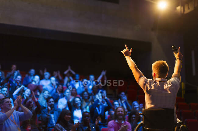 Haut-parleur en fauteuil roulant sur scène acclamant avec le public — Photo de stock
