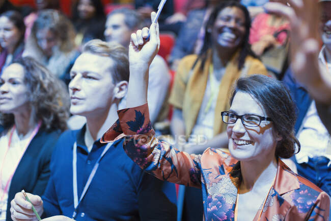 Улыбающаяся женщина в аудитории конференции поднимает руку — стоковое фото