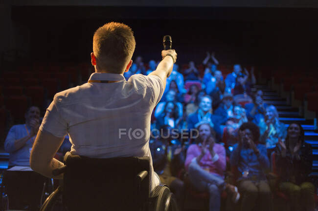 Haut-parleur féminin avec microphone en fauteuil roulant sur scène — Photo de stock