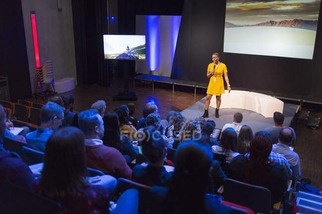 Female speaker on stage talking to audience — Stock Photo