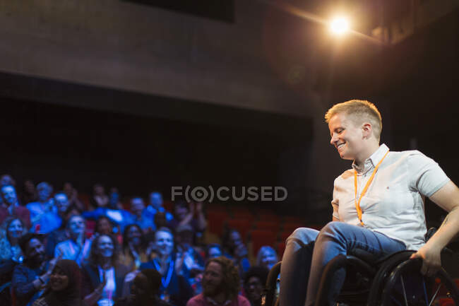 Altoparlante femminile sorridente in sedia a rotelle sul palco — Foto stock