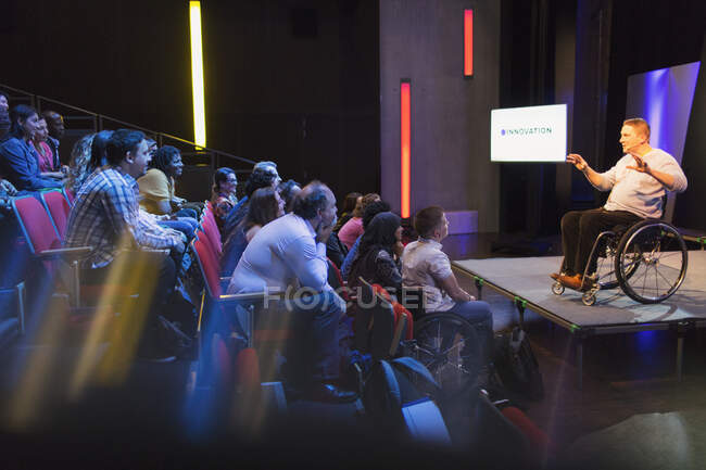 Público atento ouvindo orador feminino em cadeira de rodas no palco — Fotografia de Stock