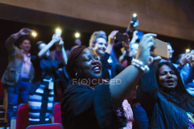 Улыбающаяся женщина с камерой телефона в аудитории — стоковое фото