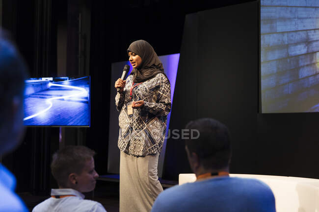 Altavoz femenina en hijab en el escenario hablando con el público - foto de stock