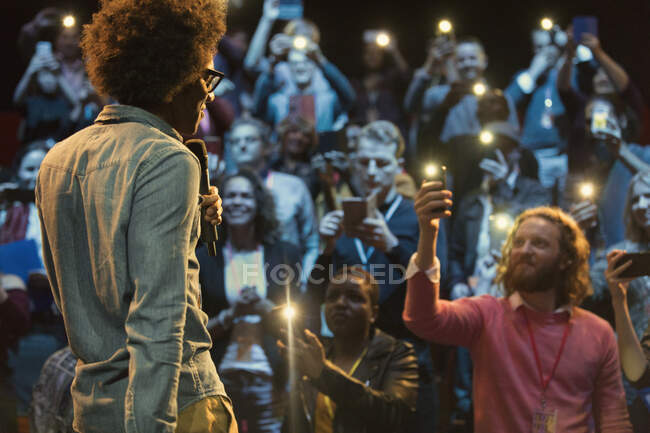 Audience using smart phone flashlights, watching speaker — Stock Photo