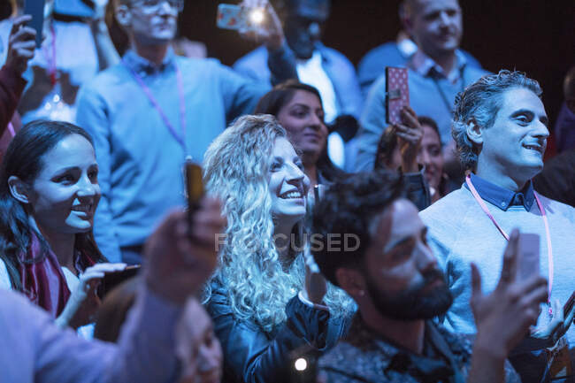 Улыбающаяся женщина с телефоном в тёмной аудитории — стоковое фото