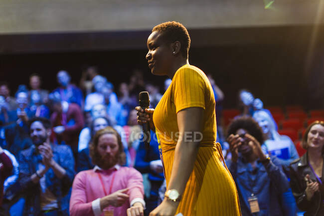 Haut-parleur féminin avec microphone sur scène — Photo de stock