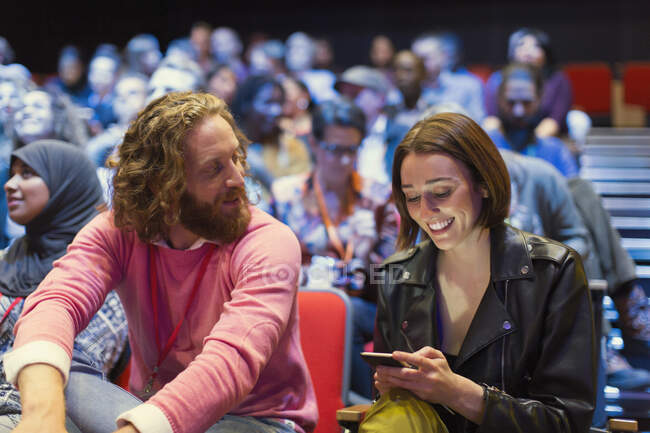 Homem e mulher com telefone inteligente na audiência da conferência — Fotografia de Stock