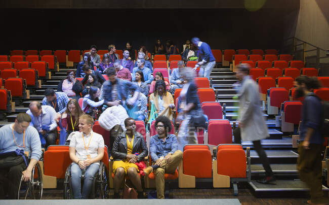 Audiencia llegando y sentándose en el auditorio - foto de stock