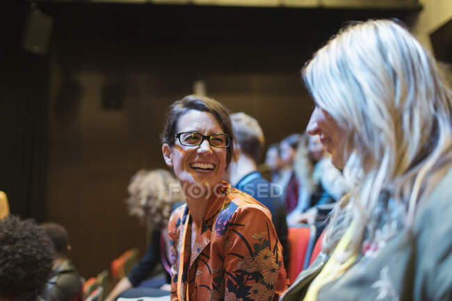 Mujeres de negocios riéndose en público de la conferencia - foto de stock