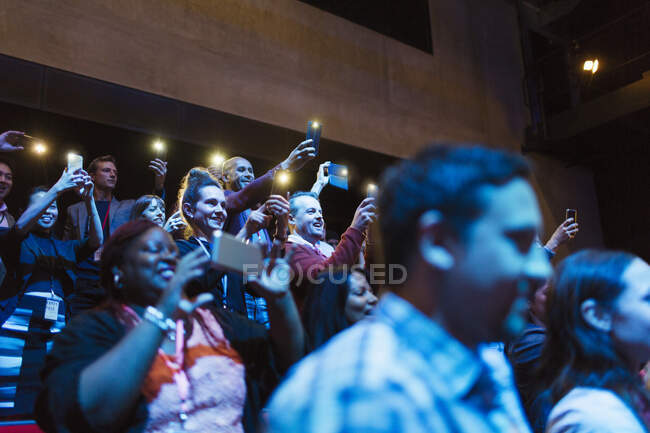 Public enthousiaste avec des téléphones de caméra dans l'auditorium sombre — Photo de stock
