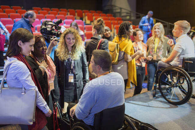 Public parlant aux conférenciers en fauteuil roulant sur scène — Photo de stock
