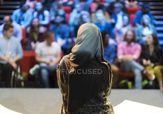 Altavoz femenina en hijab en el escenario hablando con el público - foto de stock