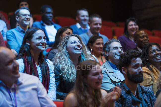 Sonriente y entusiasta audiencia en el auditorio oscuro - foto de stock