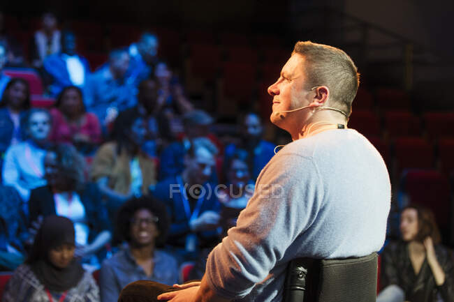 Smiling male speaker in wheelchair on stage — Stock Photo