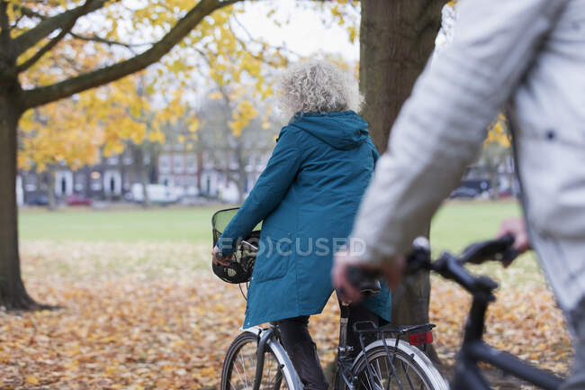 Старша жінка їздить серед осінніх листків у парку. — стокове фото