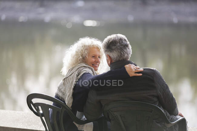 Affectionate active senior couple hugging at park pond — Stock Photo