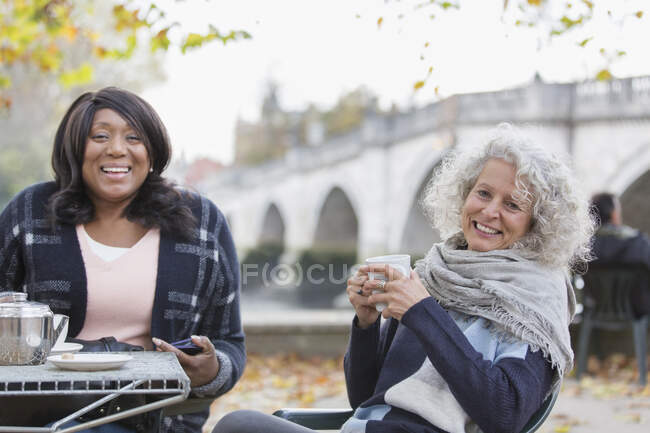 Portrait smiling, happy active senior women friends drinking coffee at autumn park cafe — Stock Photo