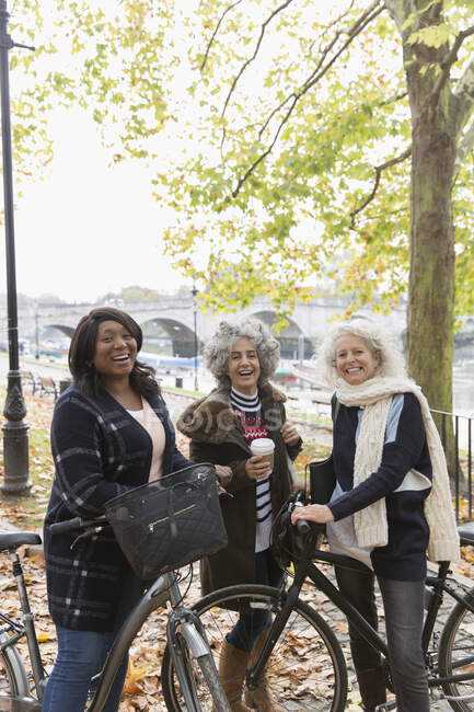 Portrait smiling, confident active senior women friends with coffee and bicycles in autumn park — Stock Photo