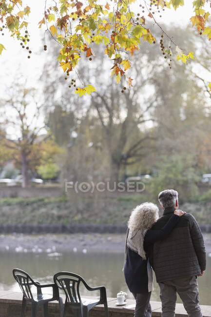 Affettuosa coppia anziana attiva al laghetto del parco autunnale — Foto stock