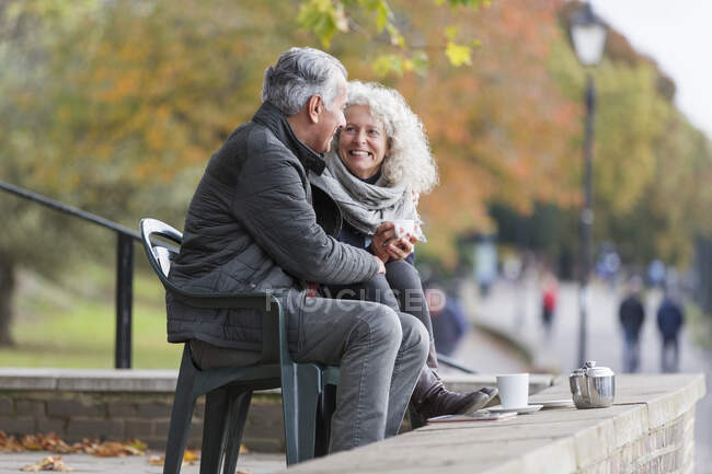 Lächelndes, anhängliches rühriges Seniorenpaar trinkt Tee im Herbstpark — Stockfoto