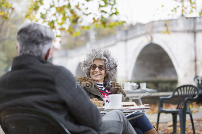Активная старшая пара разговаривает, наслаждается кофе в кафе в осеннем парке — стоковое фото