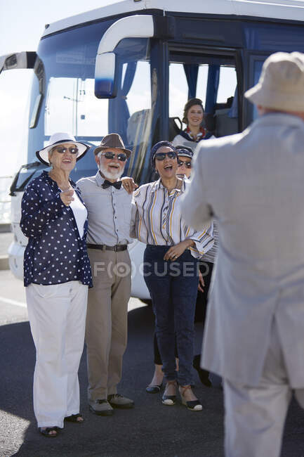 Lächelnde aktive Seniorentouristen stehen vor Tourbus — Stockfoto