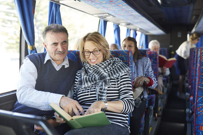 Активна старша пара туристів читає книгу на екскурсійному автобусі — стокове фото