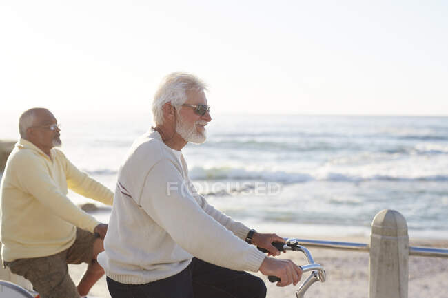 Hombre senior activo montar en bicicleta, disfrutando de la vista al mar - foto de stock