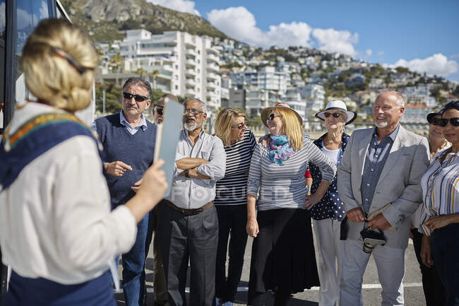 Active senior tourist friends listening to tour guide — Stock Photo
