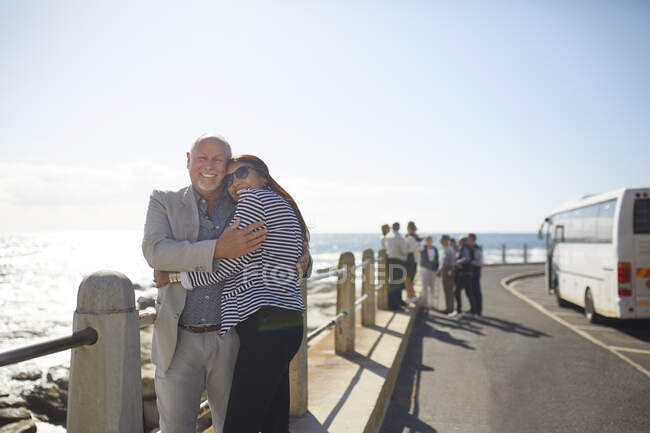 Retrato ativo casal de idosos turistas abraçando ensolarado oceano vista — Fotografia de Stock