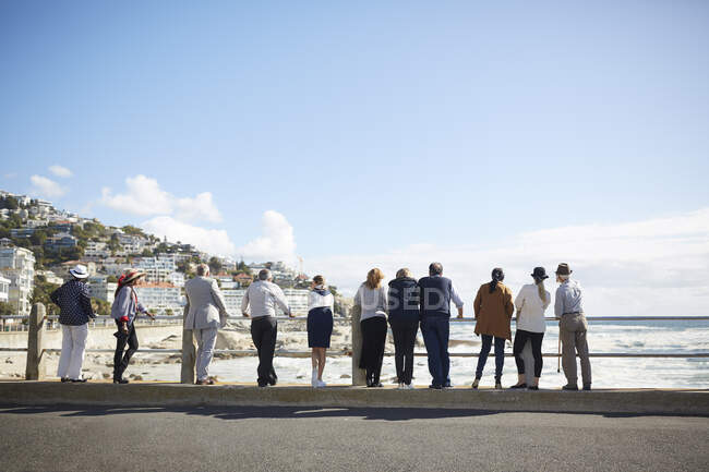 Активные старшие друзья-туристы смотрят на солнечный вид на океан — стоковое фото