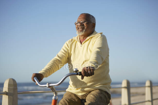 Carefree active senior man tourist bike riding along ocean — Stock Photo