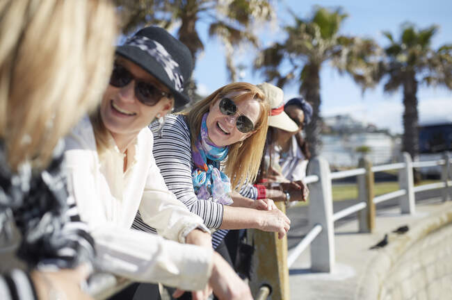 Smiling active senior women tourist friends talking on sunny boardwalk — Stock Photo